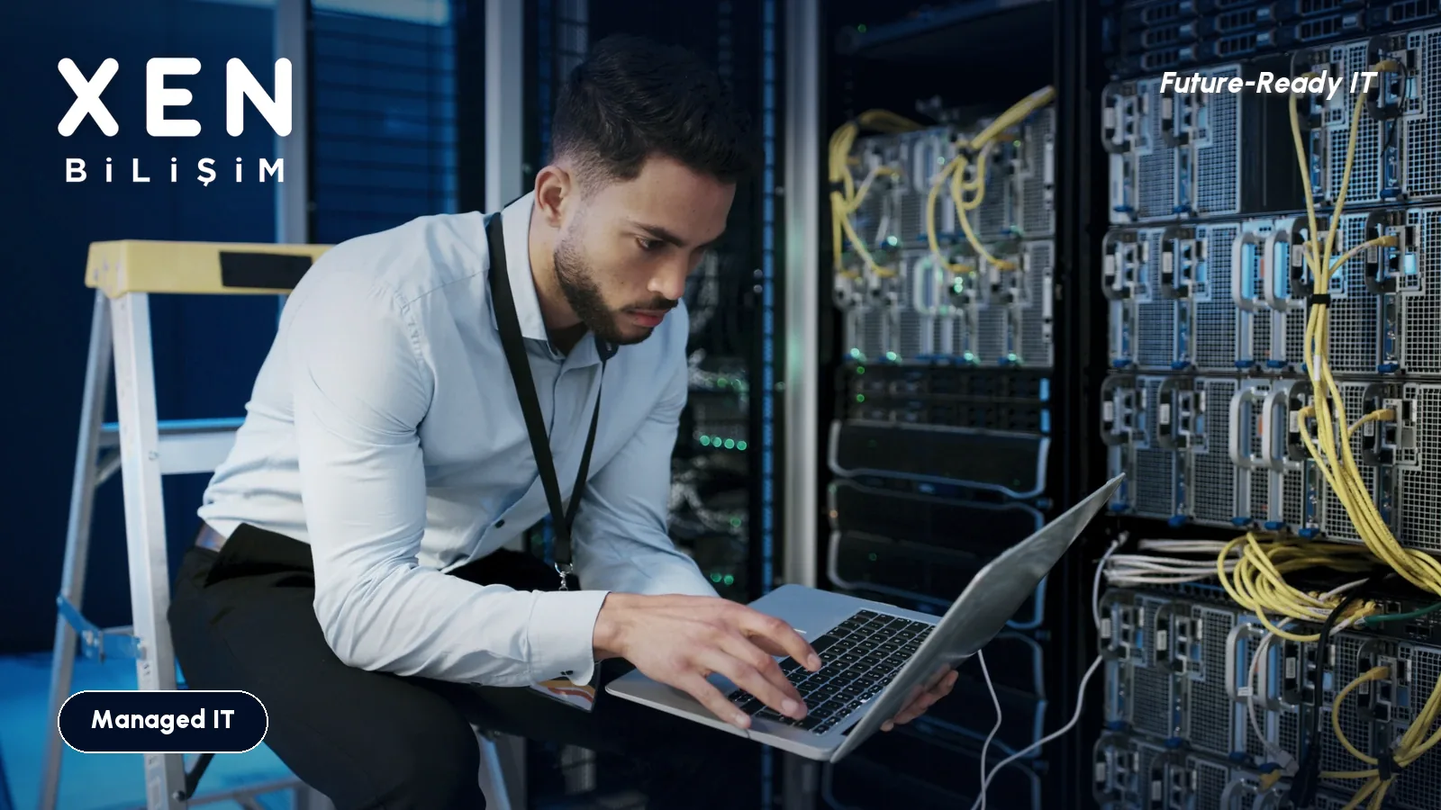 IT technician working on a laptop in a server room — Xen Bilişim