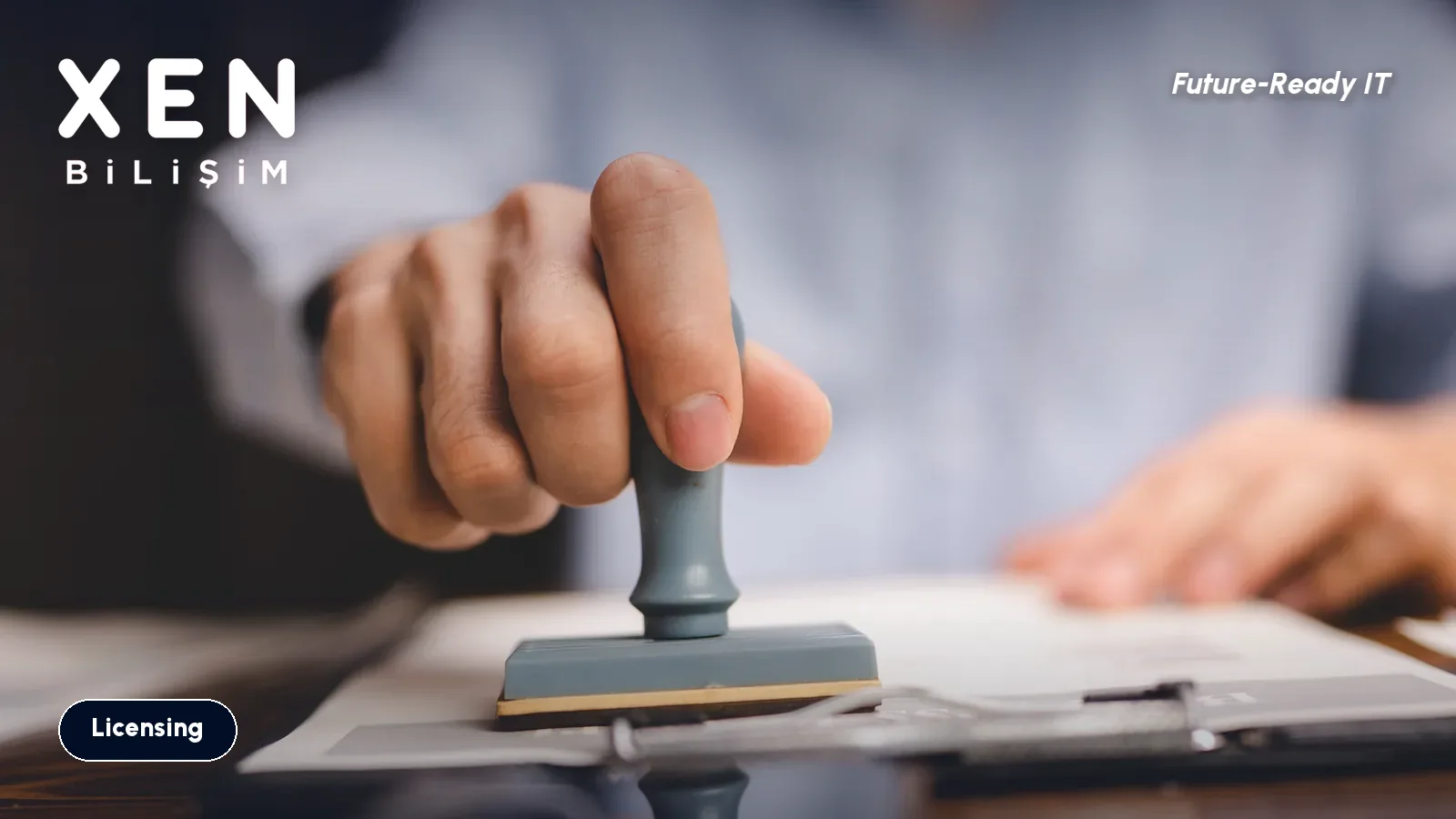 A hand stamping an official document on a desk - software license audit legal risk - Xen Bilişim